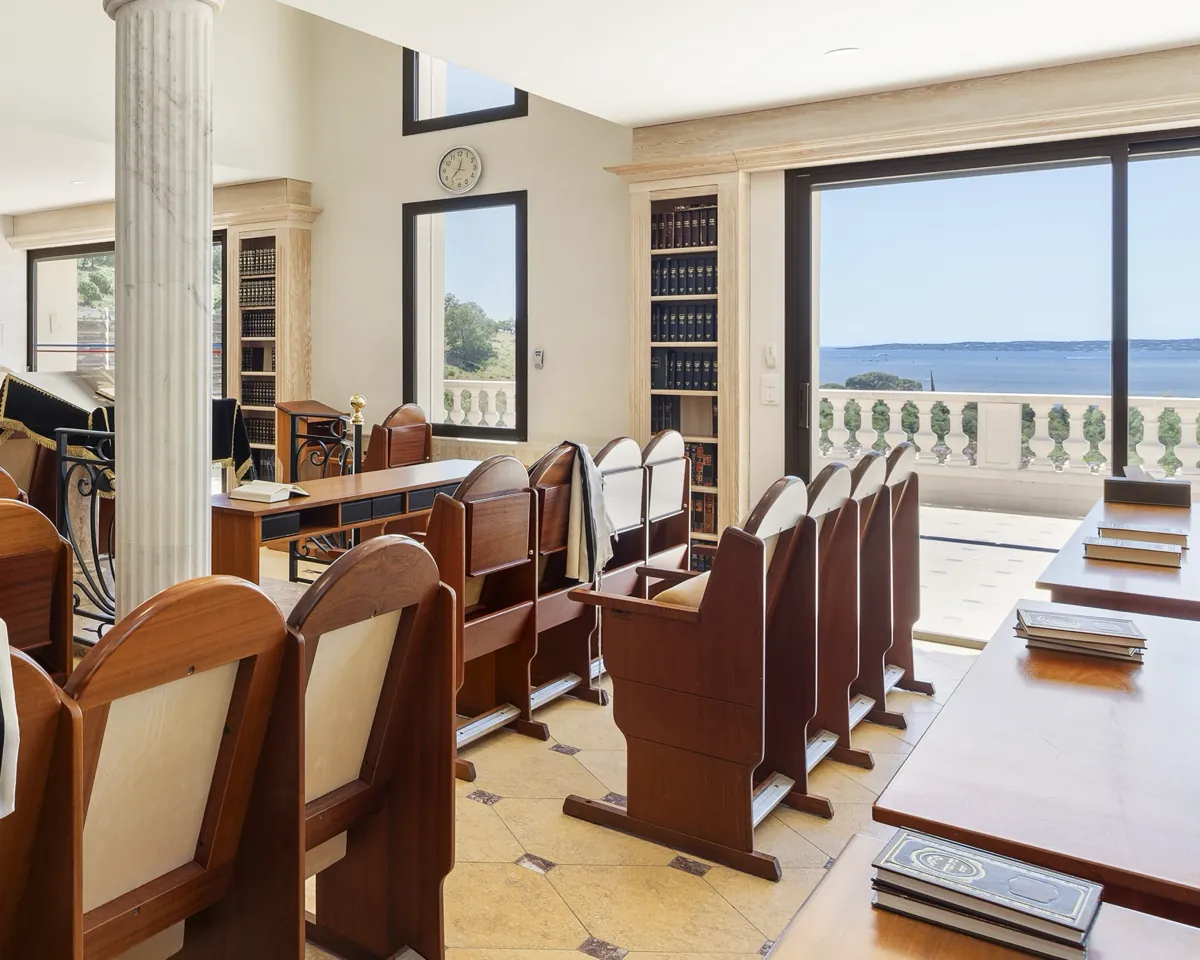 Salle de prière&nbsp;: bancs en bois, colonne de marbre, bibliothèques et grande baie ouverte sur la mer.